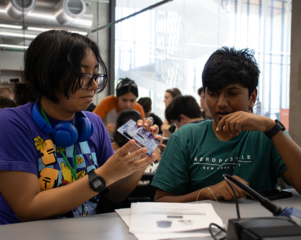 Two students working hands-on to build their robot in the robotics lab on UT Campus 