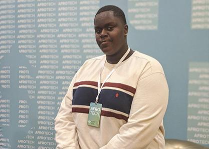 Earl Potts sits on a golden couch at the AfroTech Conference for Black students in computer science