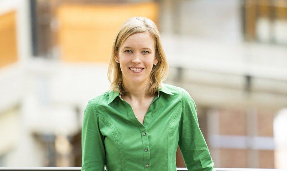 Franzi Roesner, TXCS alumnus, White woman with blonde hair in green button down shirt standing in front of a building smiling