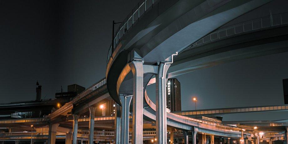 A night view of a city scene with multiple highway overpasses overlapping. 