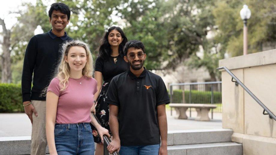 Four undergraduate students, Prasann Singhal, Nihita Sarma, Shankar Padmanabhan and Jennifer Mickel pose on a staircase near a limestone building at UT.