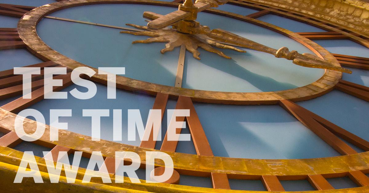 Close up of UT Tower clock face with "Test of Time Award" text in bottom left corner.