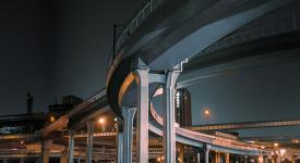 A night view of a city scene with multiple highway overpasses overlapping. 