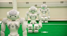 Three Nao humanoid robots lined up on RoboCup practice field.